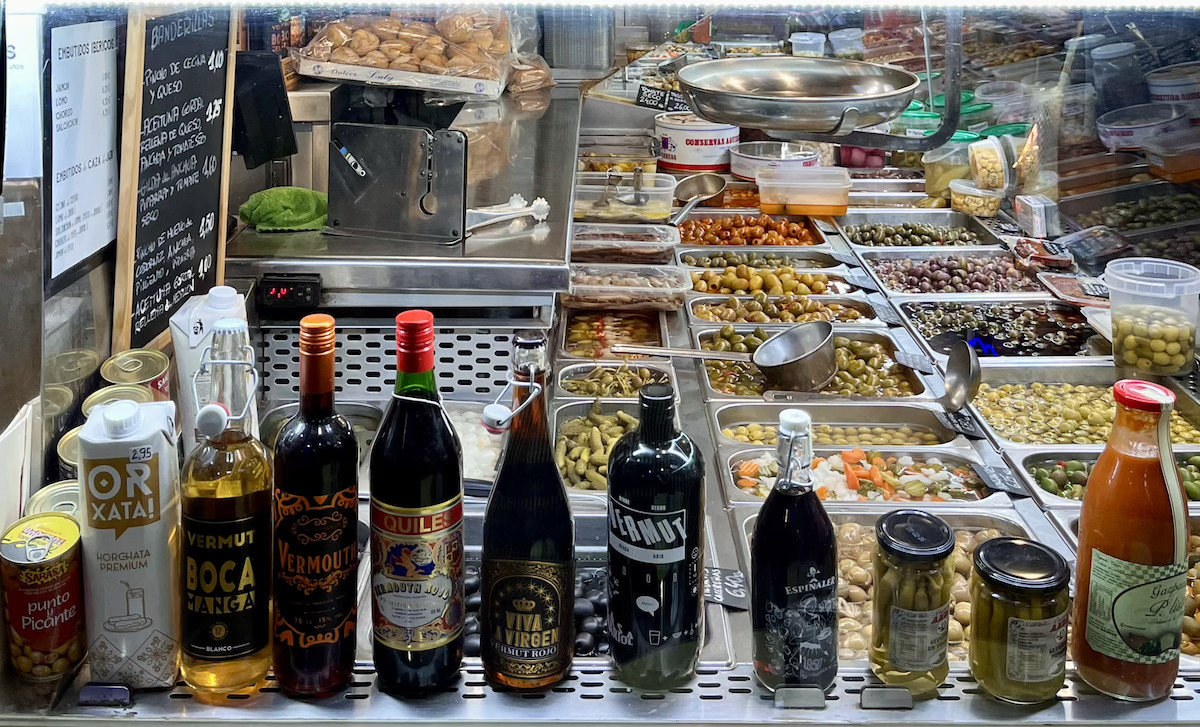 olives and jars and bottles of things being sold in a market