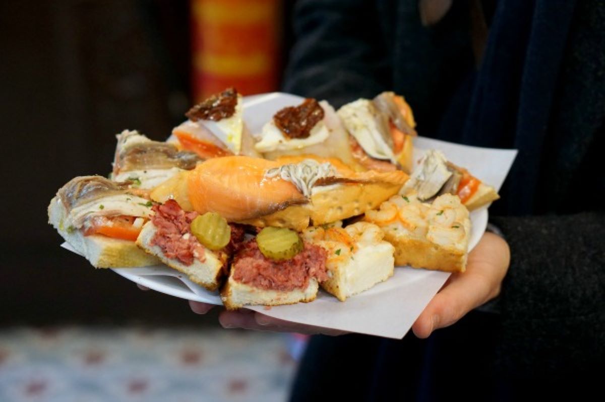 a man serving a plate with various toasts with different toppings