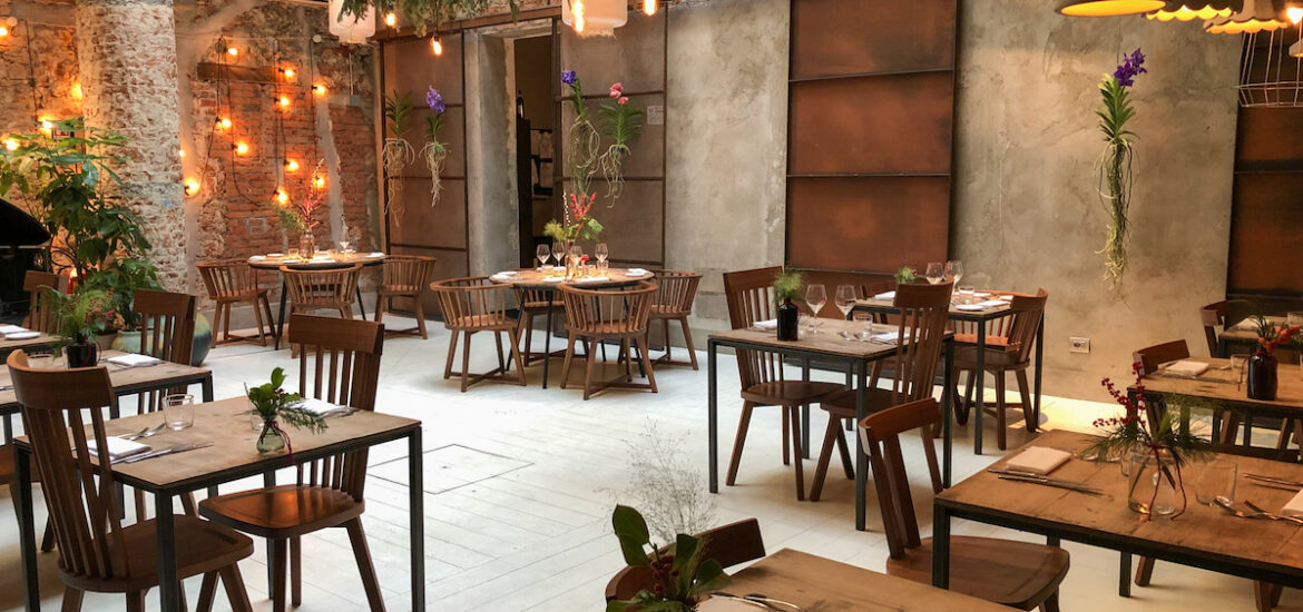 Dining space with rustic wooden tables and chairs decorated with plants