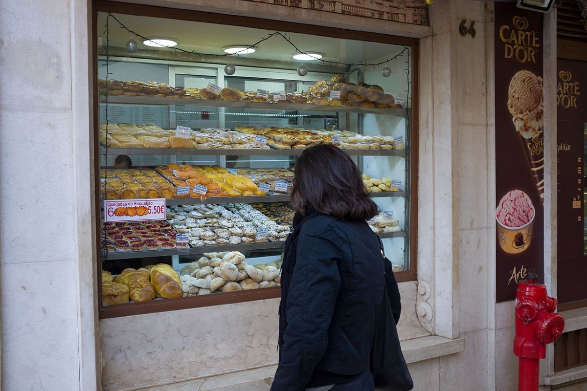 A woman looking at a bakery window in Lisbon. 