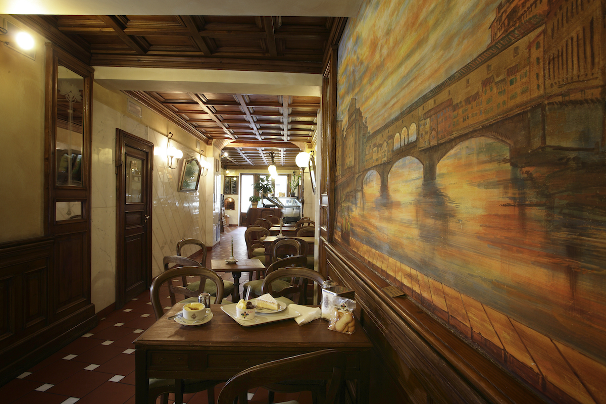 Interior of a historic ice cream shop with dark wood paneling and a painting of a bridge on the right hand wall