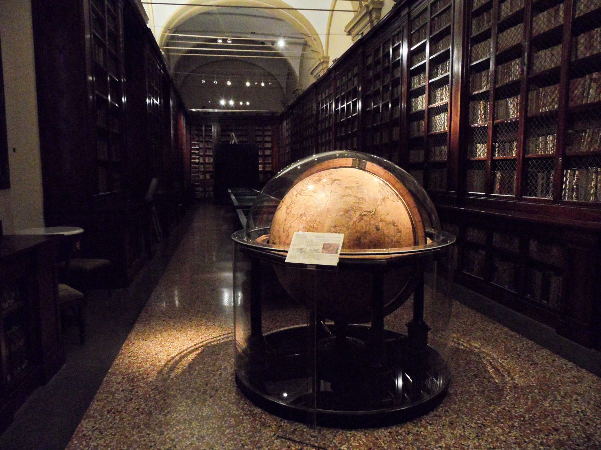 dark room with bookshelves on the walls and large globe on stand in the middle of the room