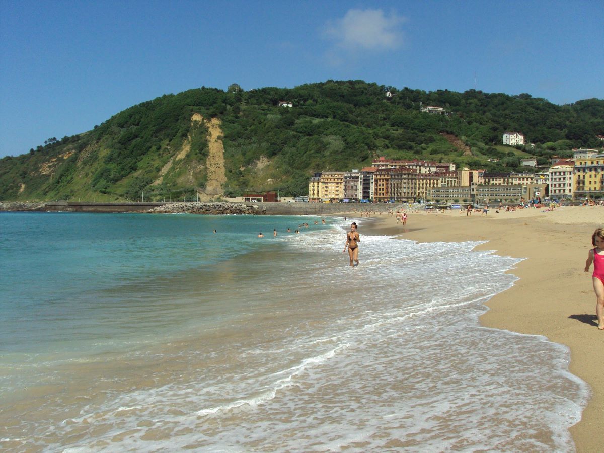 people hanging out at Zurriola beach where people are surfing