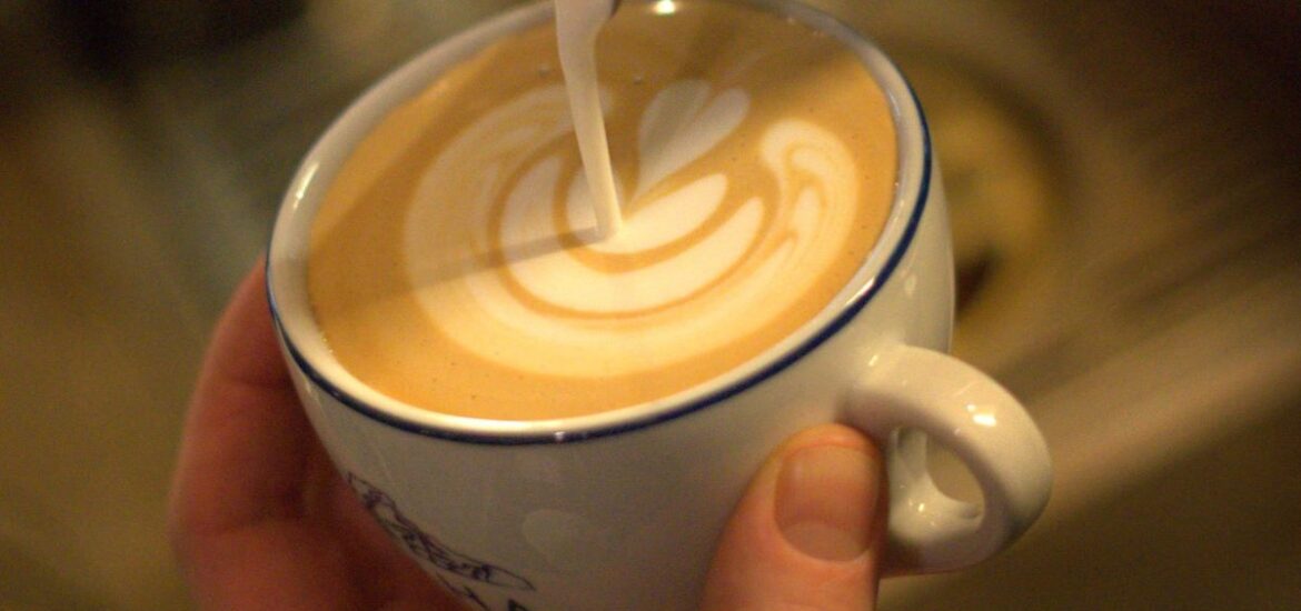 up-close shot of milk being poured into coffee cup