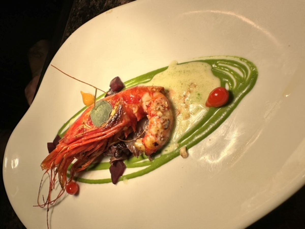 white plate with creamy green sauce topped with large shrimp