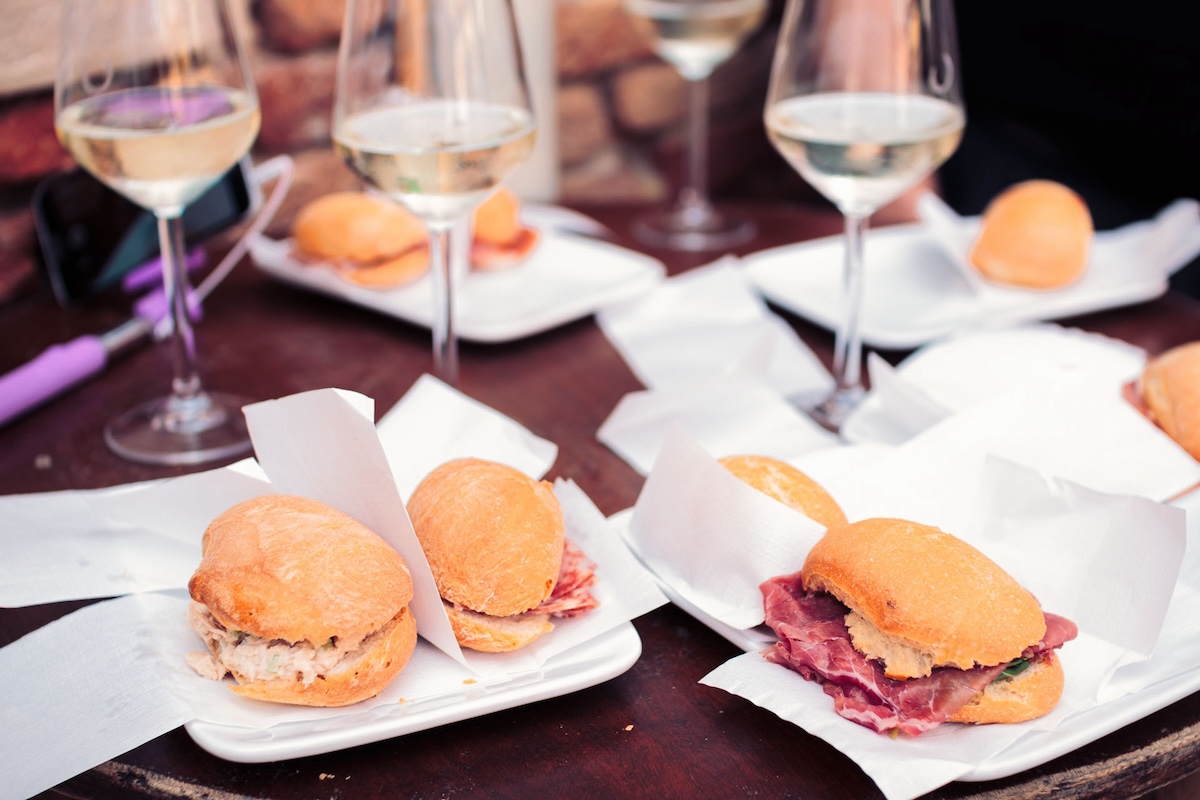 table topped with plates of small sandwiches and wine glasses