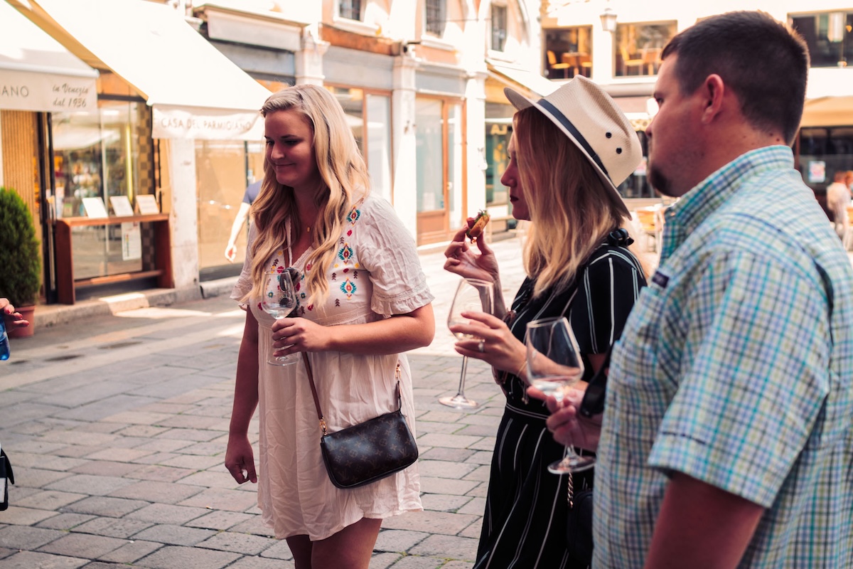 three people on the street with wine glasses in their hands