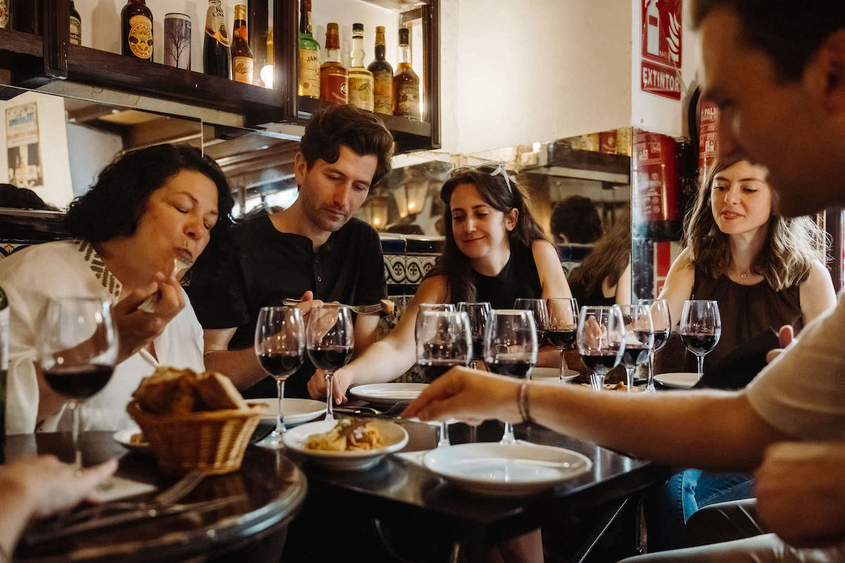 Group of people with red wines trying tapas.