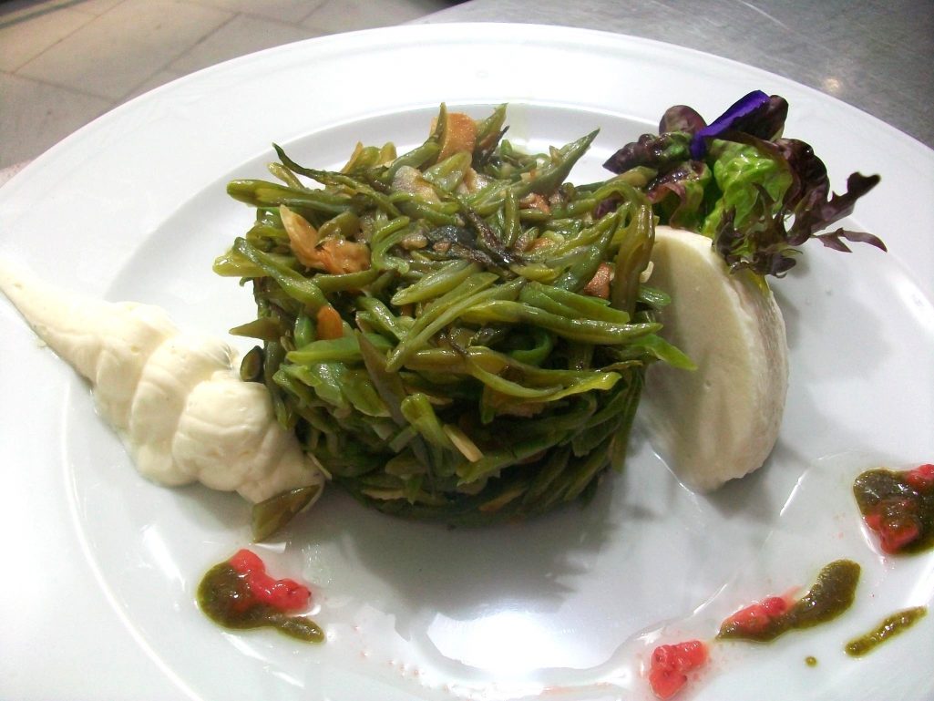 green beans with cheese on a white plate with lettuce.