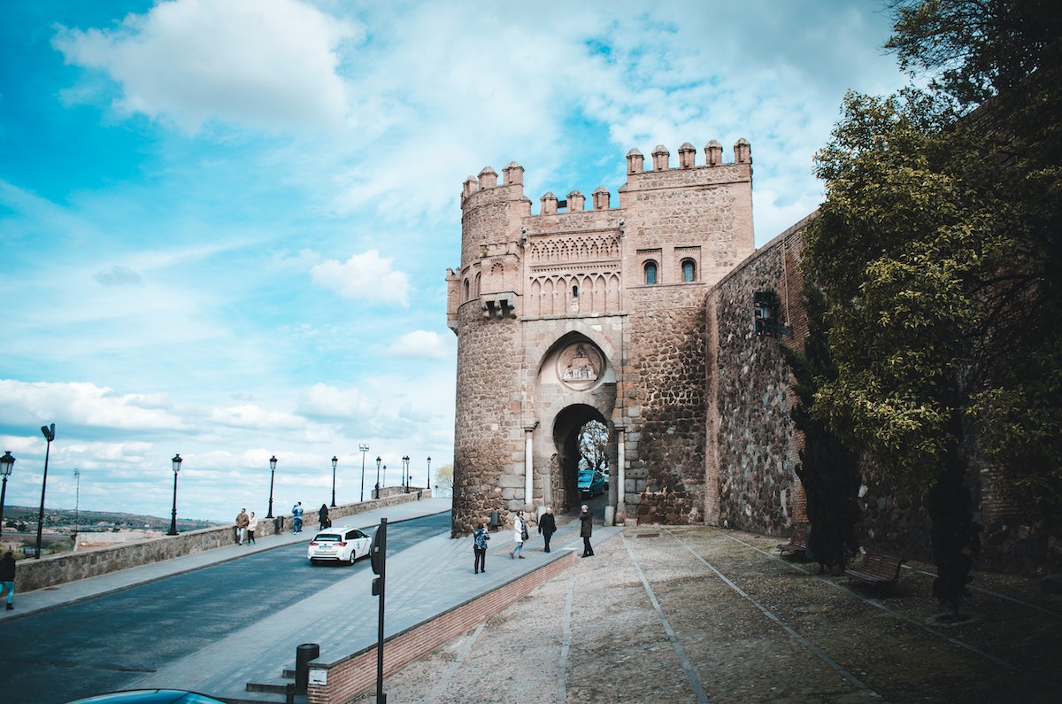 Large historic stone tower next to a city street.