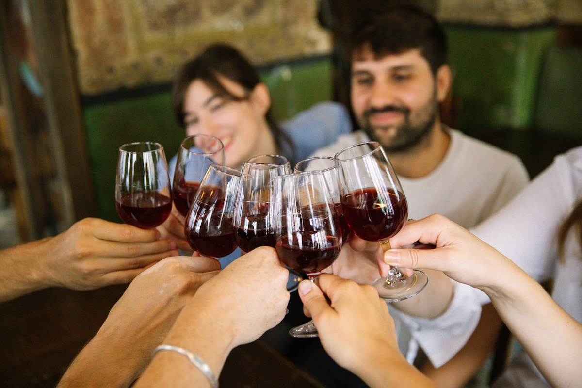 people toasting with glasses of red wine.