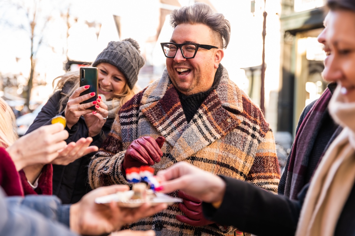 People laughing and smiling while enjoying traditional Dutch food in Amsterdam.