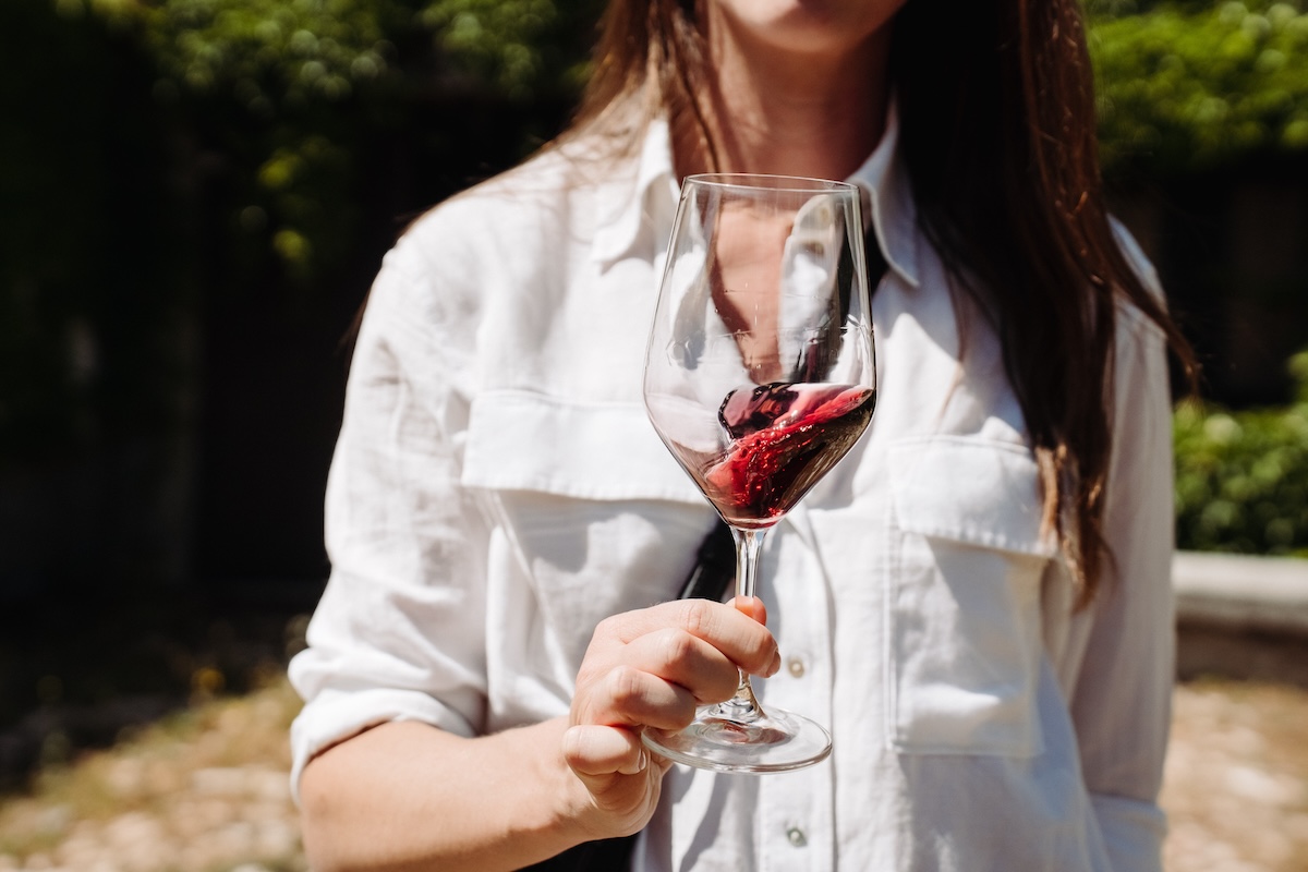 woman swirling a glass of red Spanish wine with a Denomination of Origin in Spain seal. 