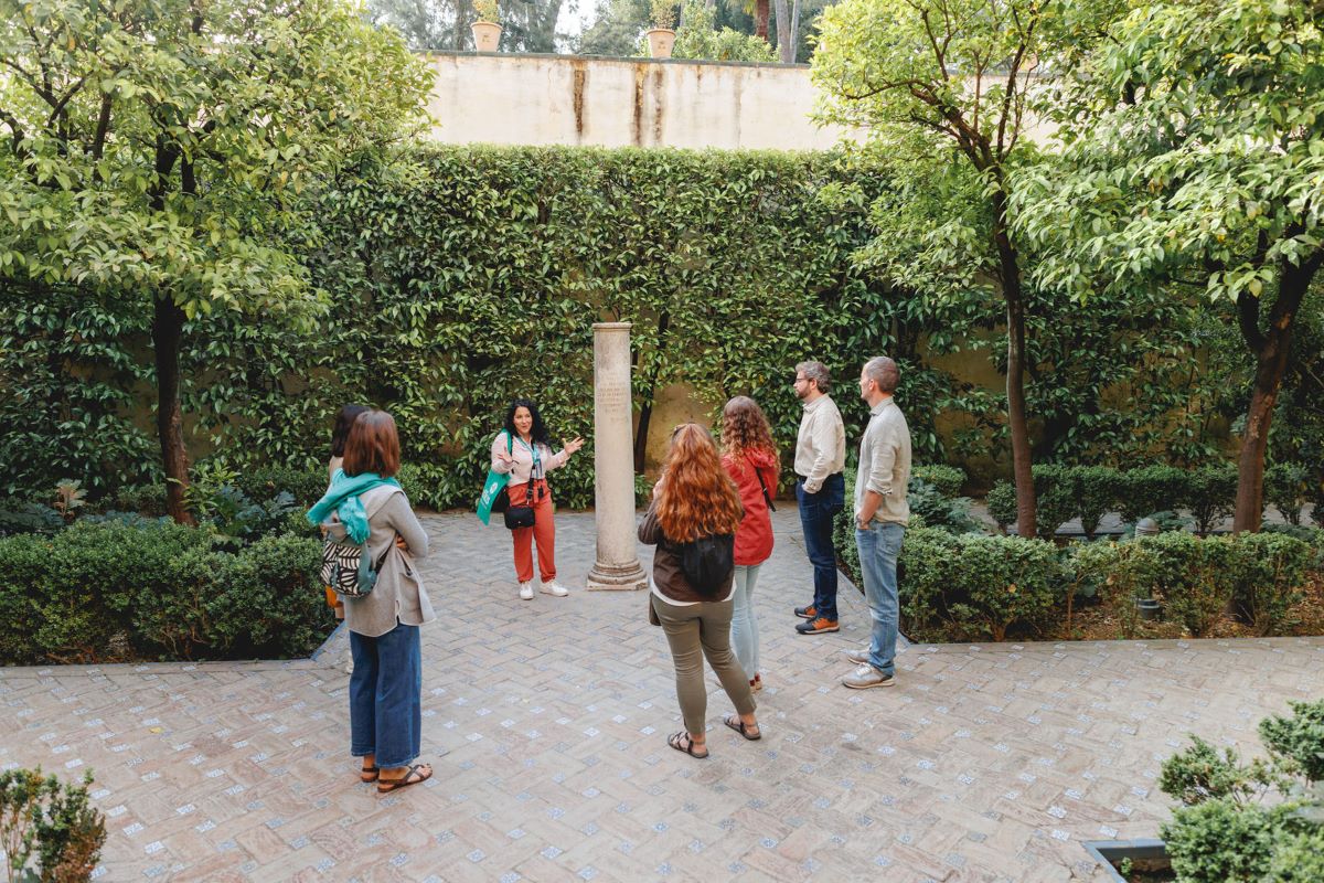 A group gathers inside the gardens in the Real Alcazar of Seville