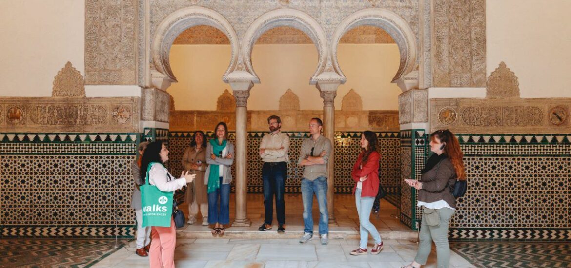 A group intently listen a guide as she shares history on Seville's Alcazar