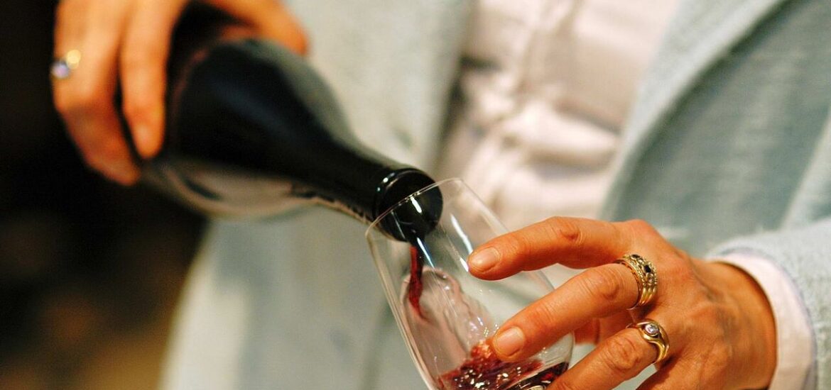 A person pouring a glass of red wine.