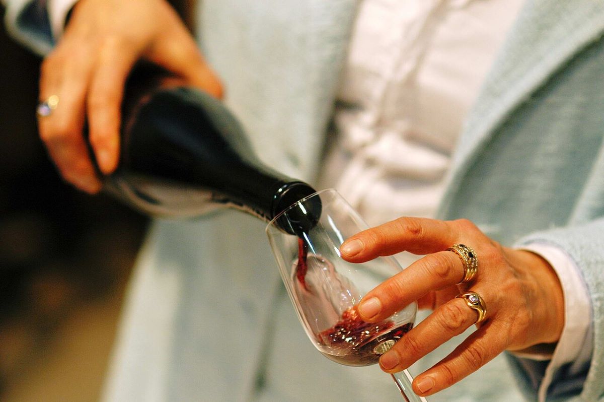 A person pouring a glass of red wine.