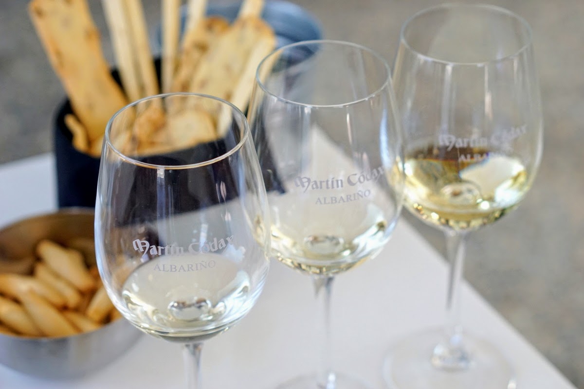 Three glasses of white wine in front of a basket of breadstick crackers.