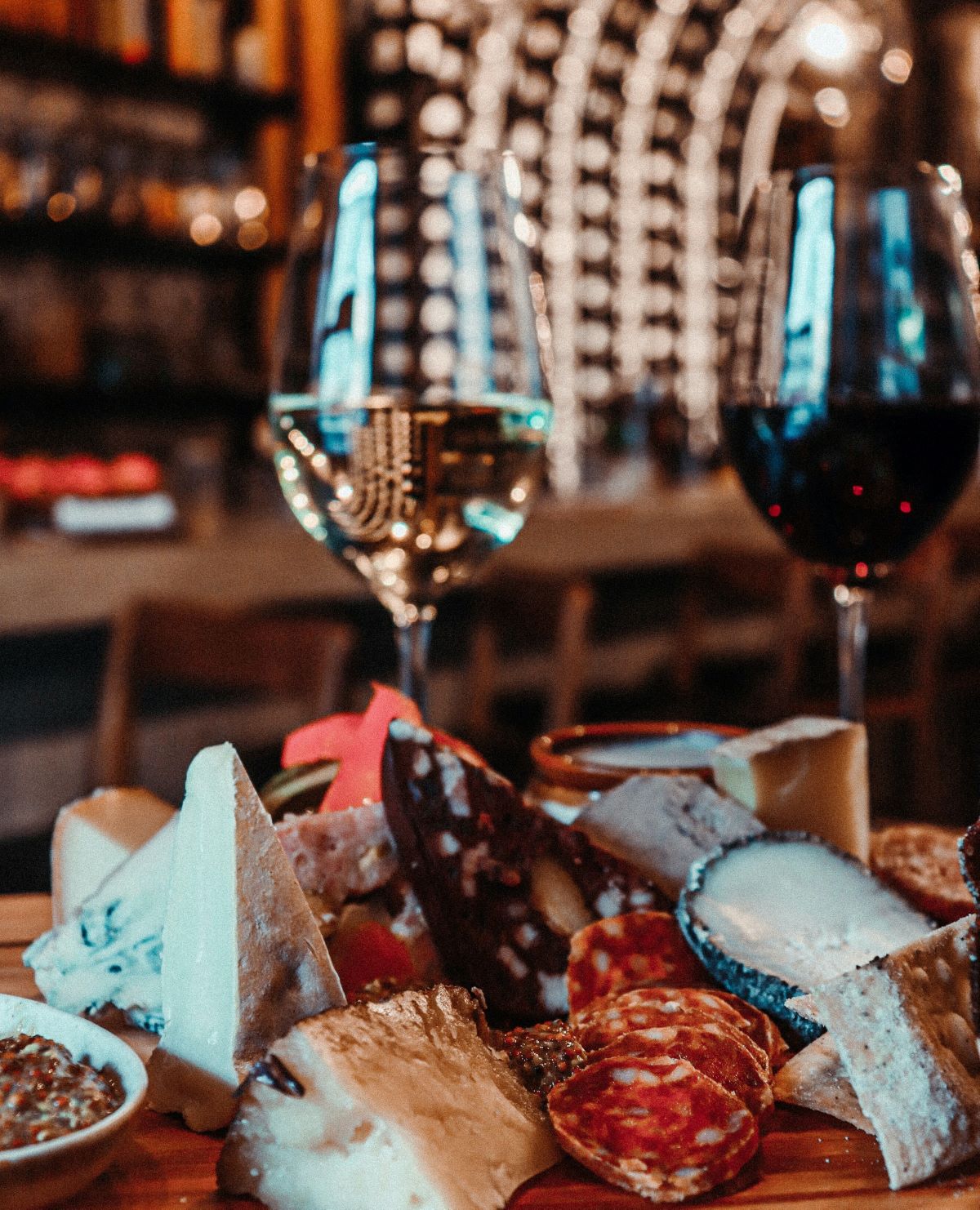 cheese and charcuterie board next to glasses of red and white wine