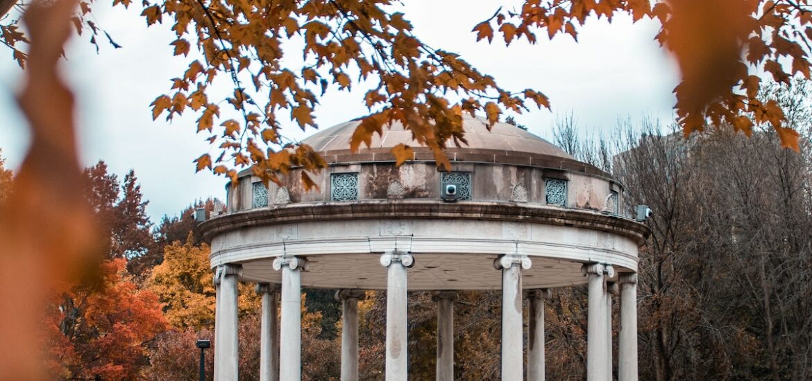 A white and blue gazebo hides behind a frame of orange leaves in the Boston Common