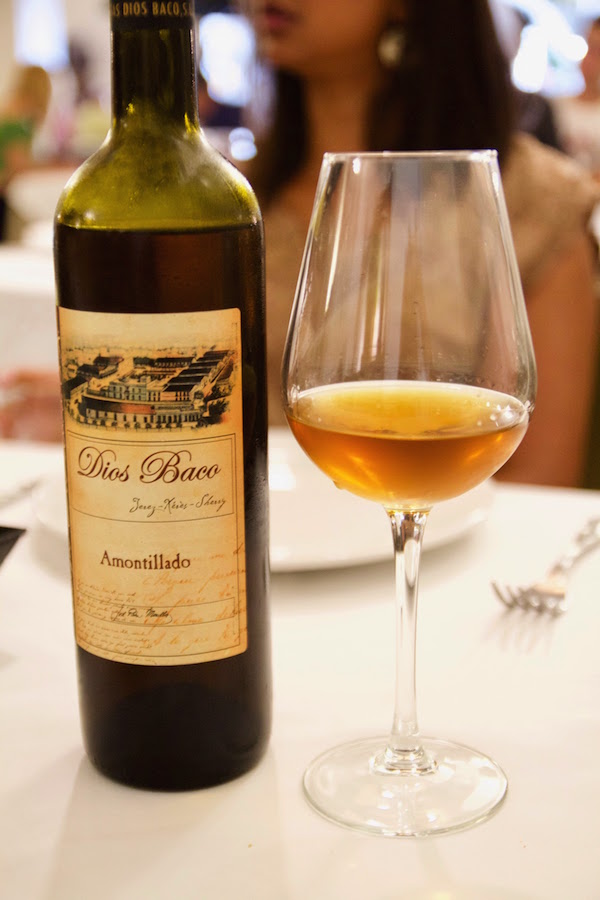 Close up of a group of people holding glasses of brown amontillado sherry wine at one of the best sherry bars in Madrid.