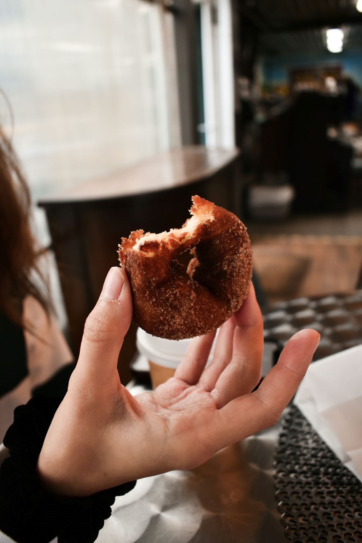 Woman with red nails holding a sugar doughnut.