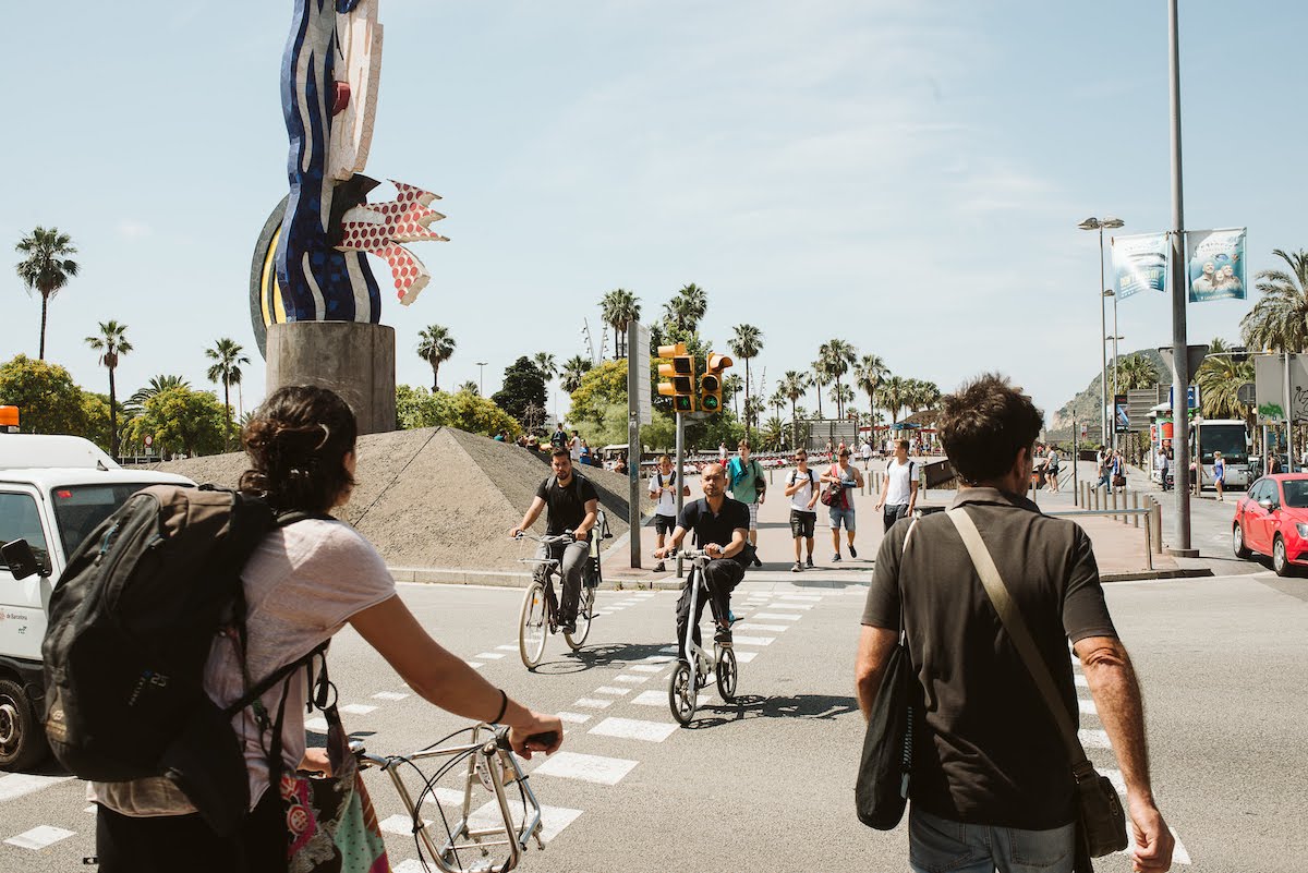 Pedestrians and bikers crossing the street at an urban intersection.