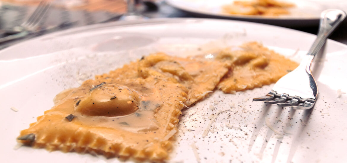 Three ravioli beside a fork on a white plate