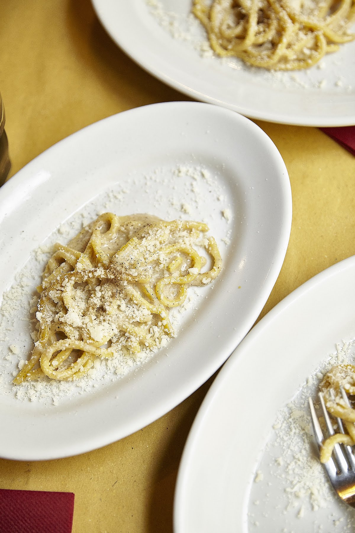 Overhead shot of cacio e pepe pasta on a white oval-shaped plate
