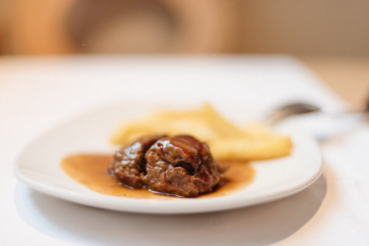 Meat in sauce and french fries on a white plate.