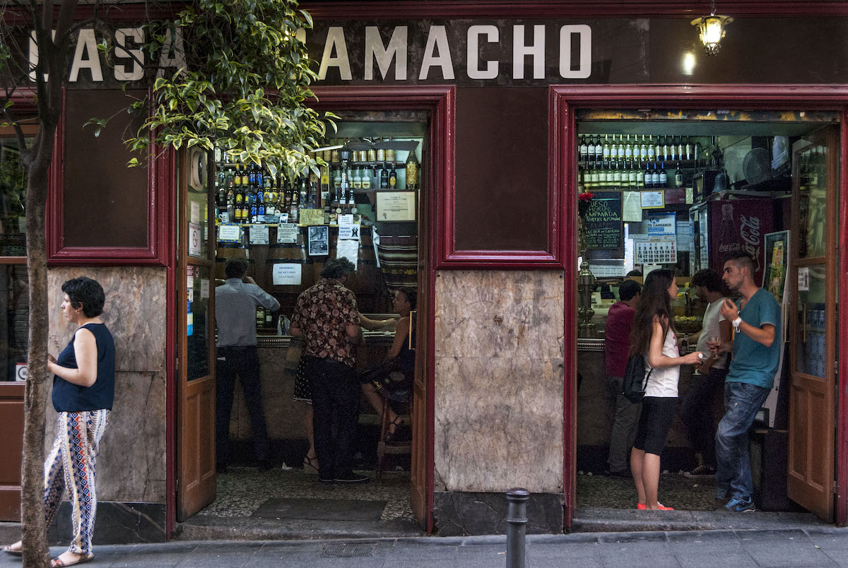People standing in the doorway of a red restaurant in Malasaña with lettering reading Casa Camacho.