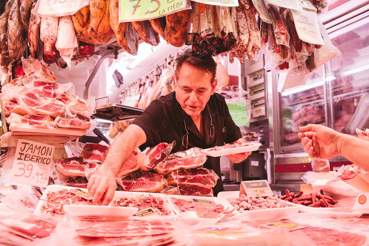 A market vendor working at a charcuterie stall.