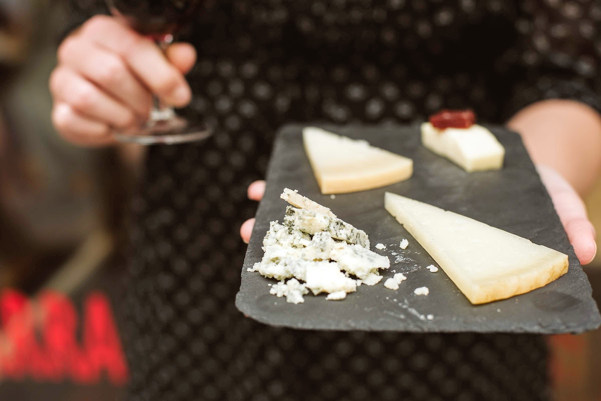 Close up of four different kinds of cheese on a black tray.