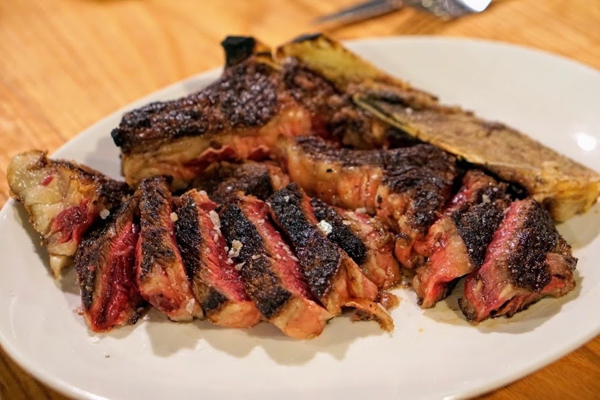 T-bone steak cooked medium rare on a white plate