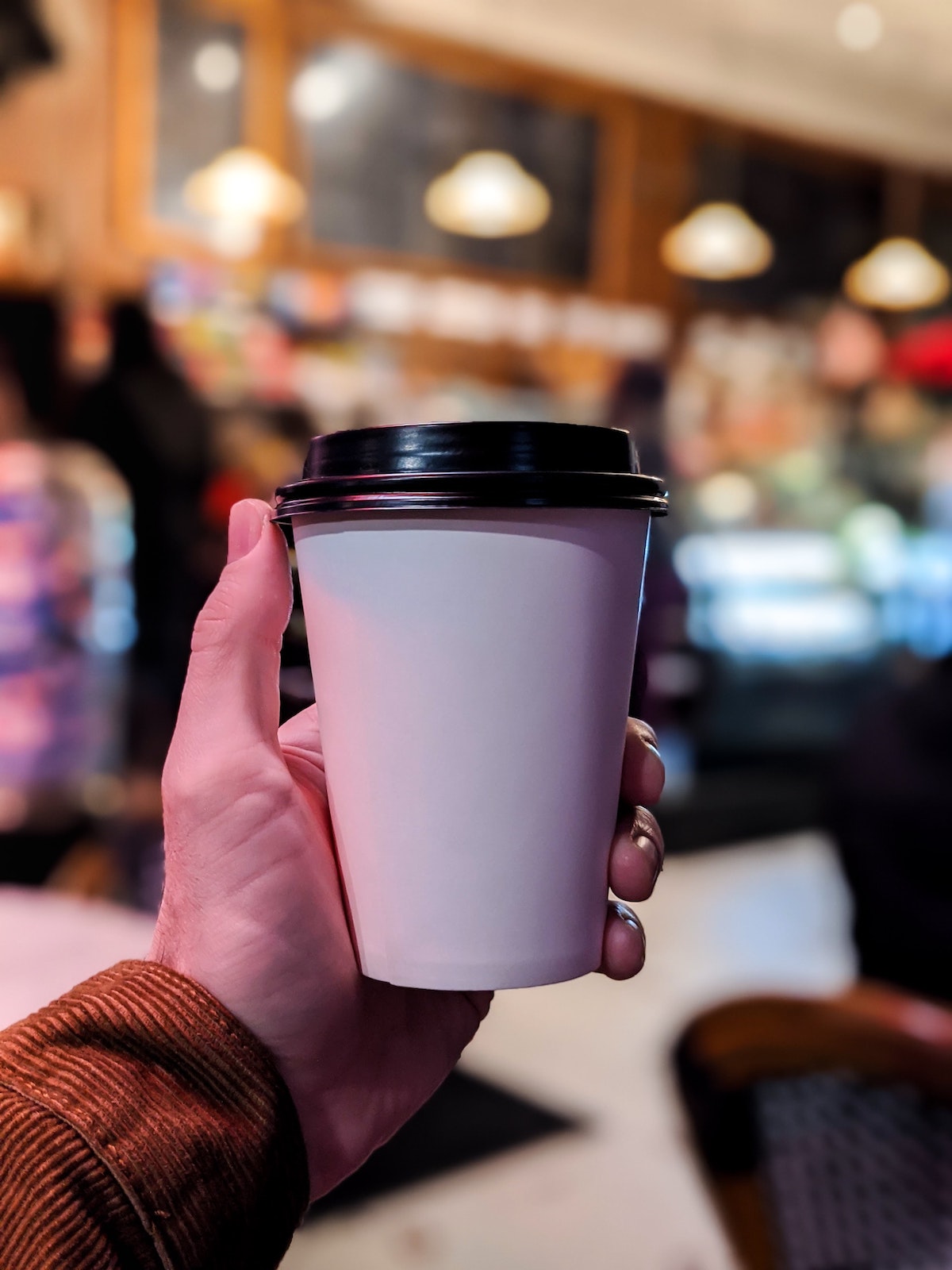 A person holding a cup of coffee in a to go cup. 