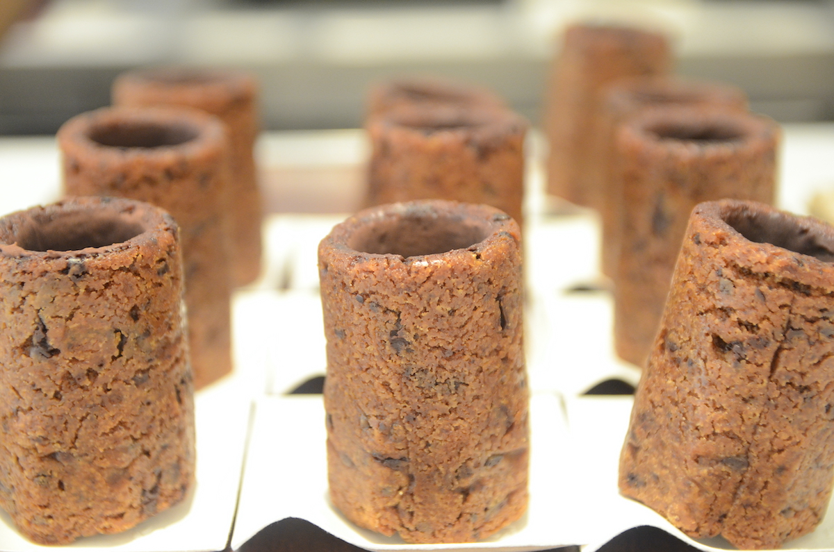 Small cylinder-shaped chocolate chip cookies standing on a white tray