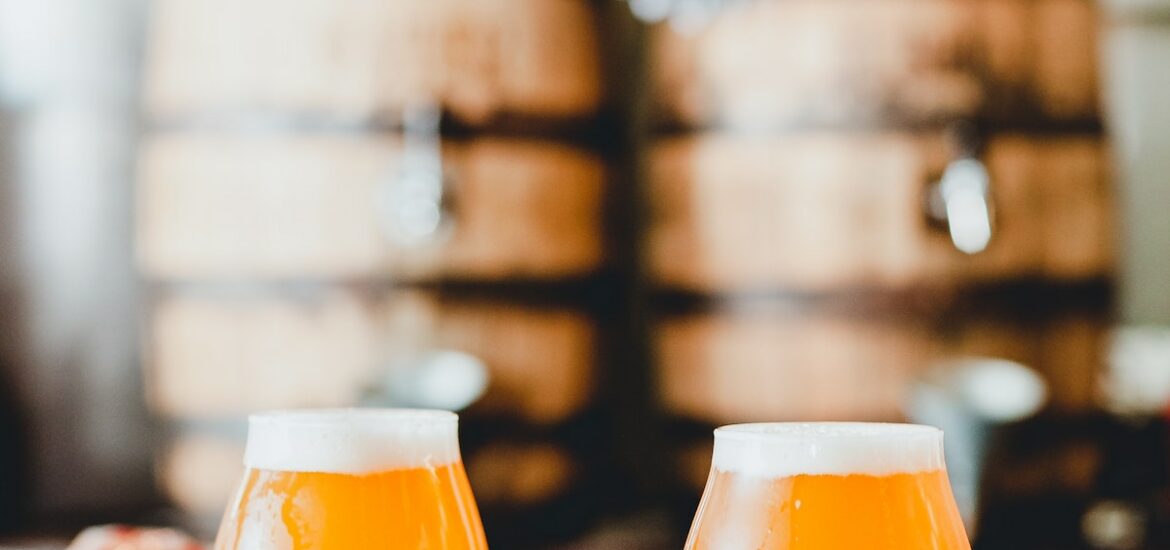 Two light colored beers on a white tabletop