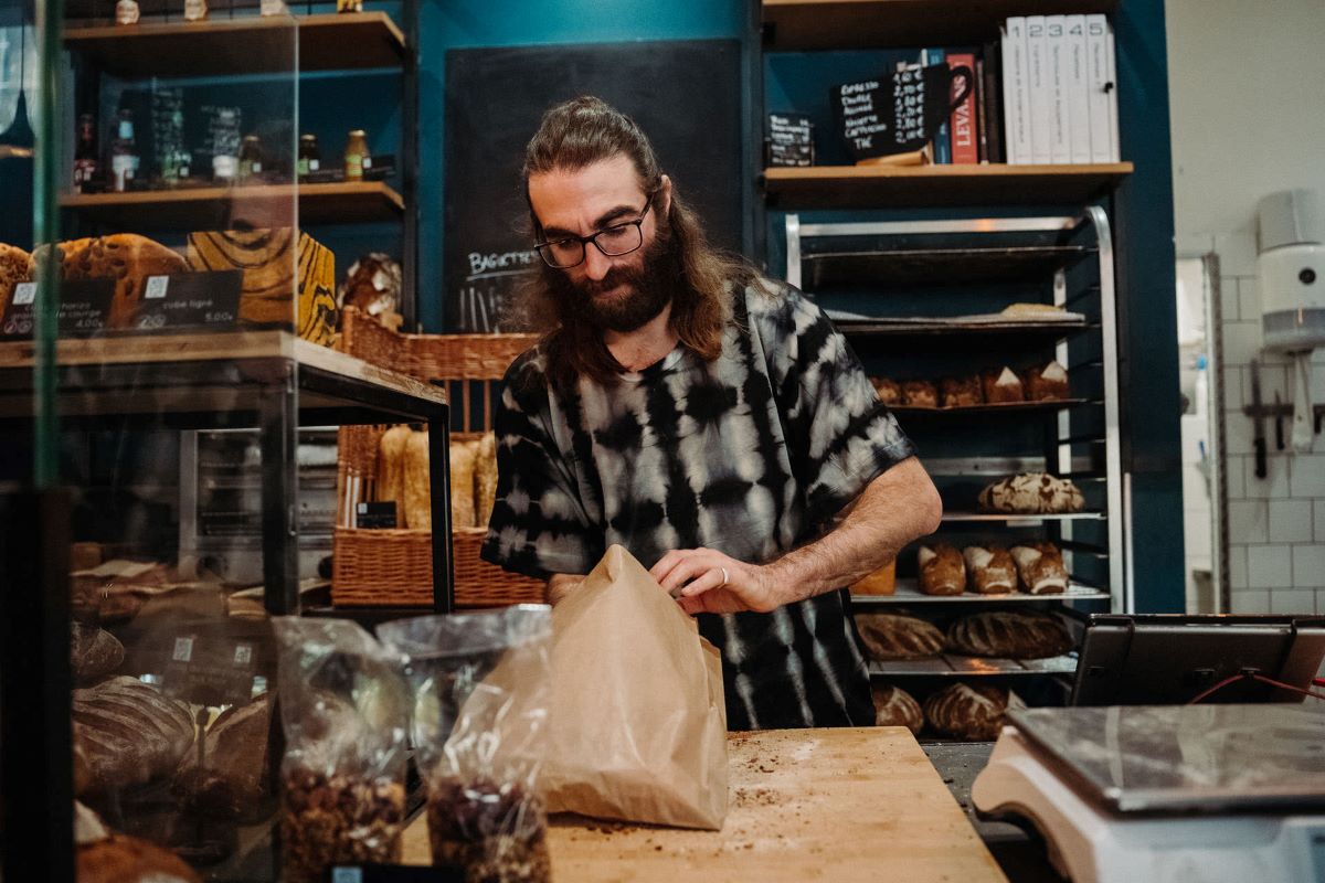 A worker packing a bag of baked goods and sweets at a shop in Bordeaux.