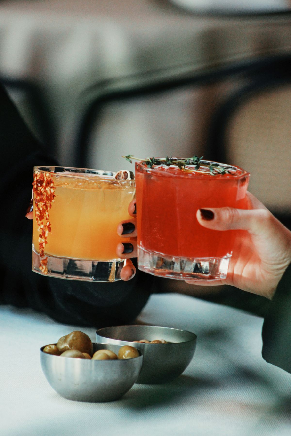 Two people with bright cocktails cheering and enjoying the nightlife in Bordeaux.