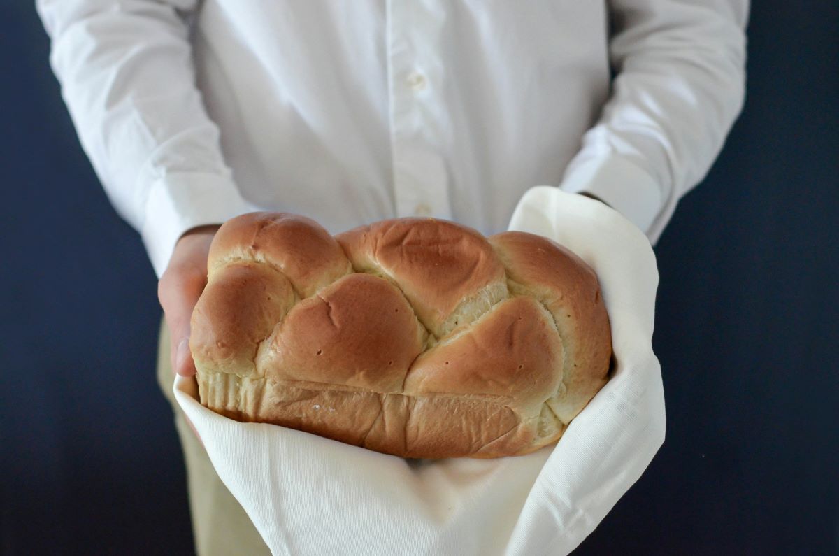 A baker holding a freshly baked brioche. 