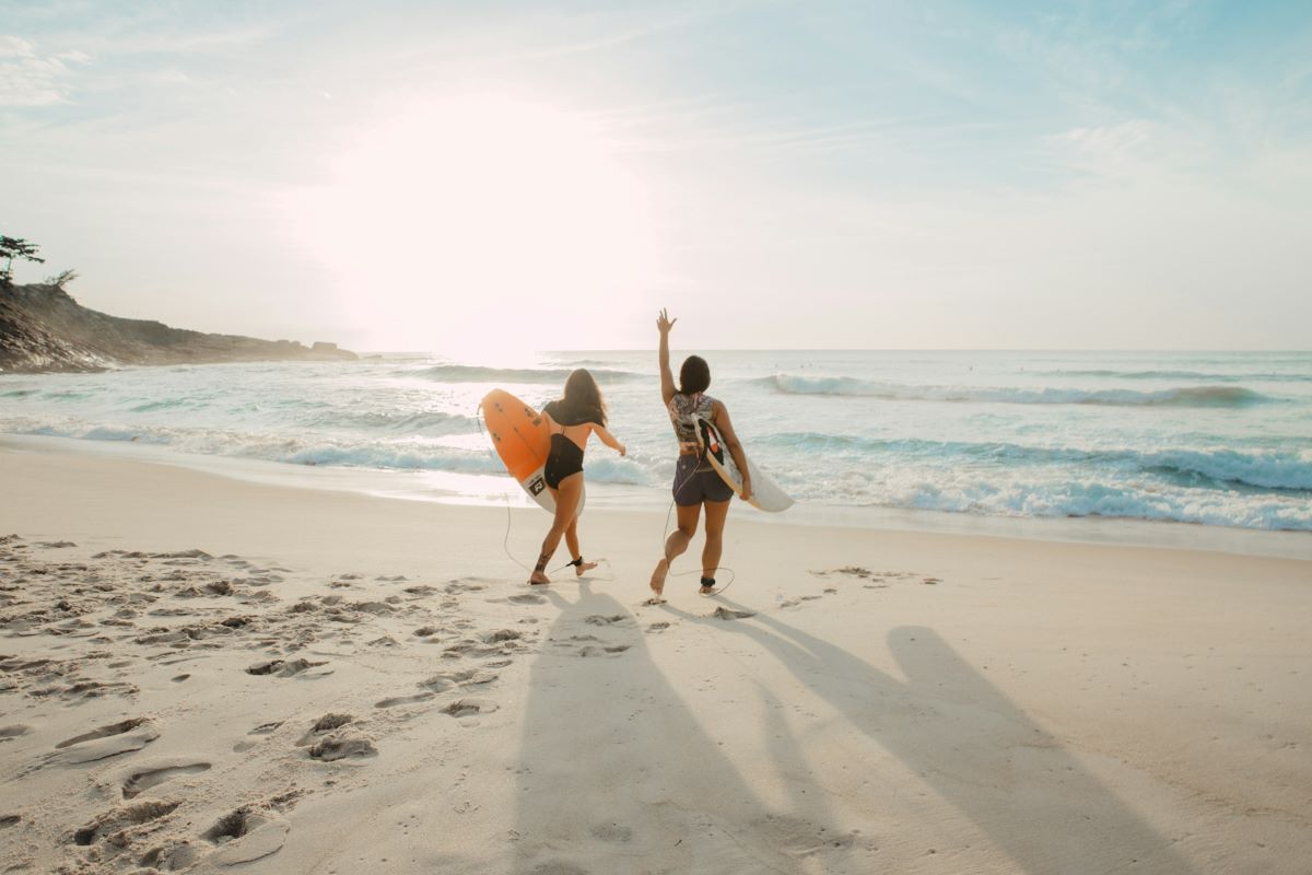 two woman walking on a beach in Seville with surfboards. 