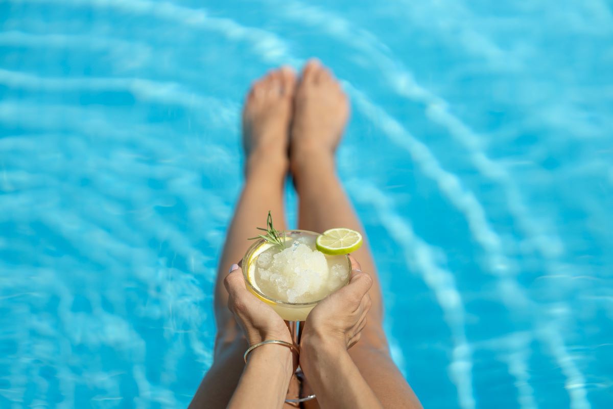 A woman holding a cocktail and hanging out in a pool. 