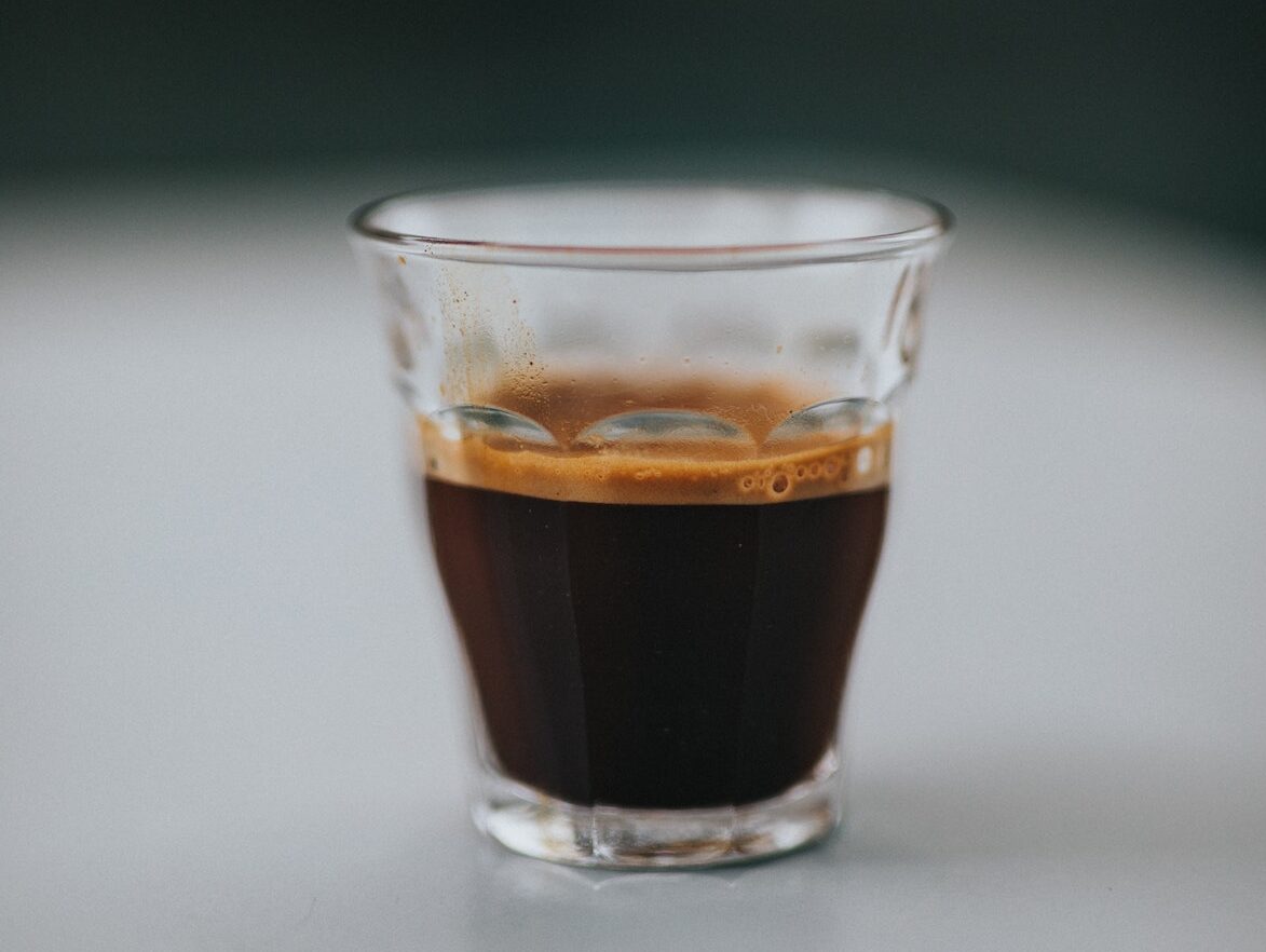 Small clear glass of espresso on a white table