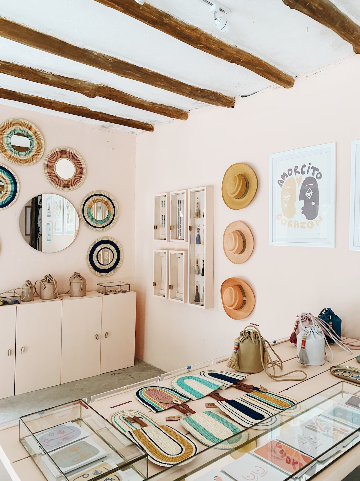 Artwork, bags, and hats on display inside a brightly lit boutique that you can go shopping at in Madrid