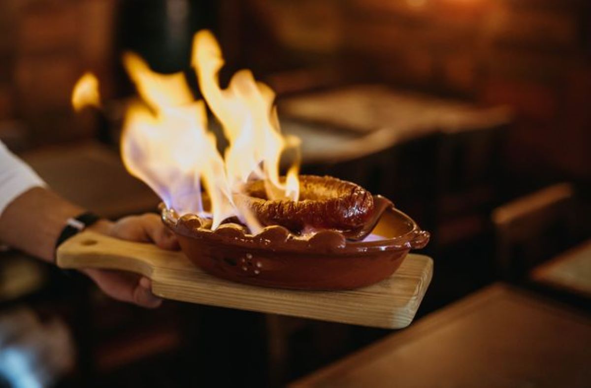 a wooden board with a plate of flaming sausage