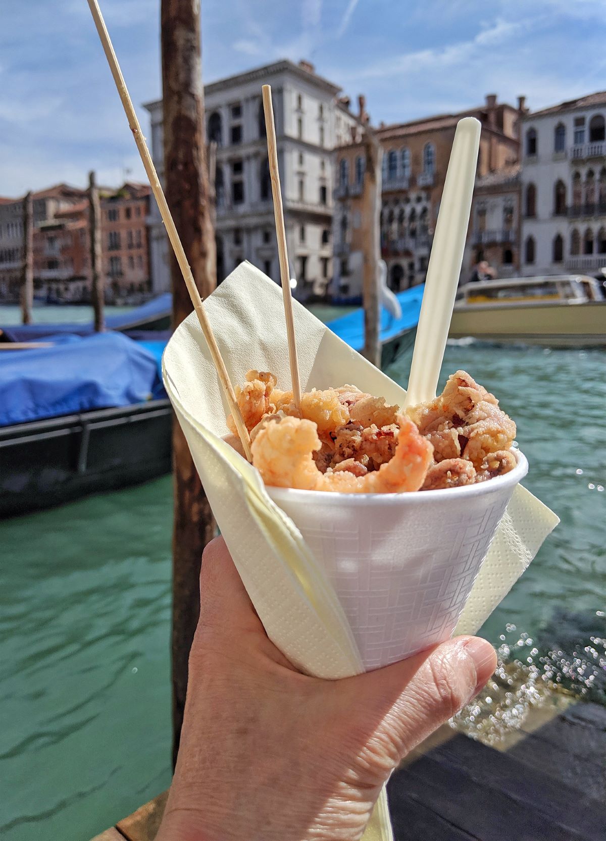 someone holding cone of fried dish