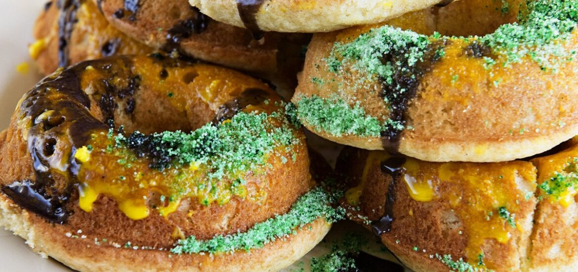 Platter of mardi gras donuts with beads and bright colors and sprinkles