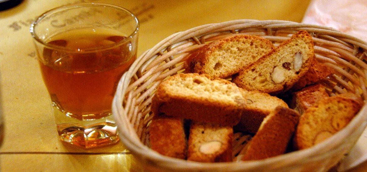 A basket of hard, yellow cookies and a small glass of amber liquid