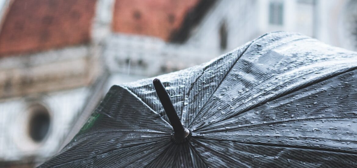 View of Florence, Italy's cathedral dome as seen from above a black umbrella on a rainy day