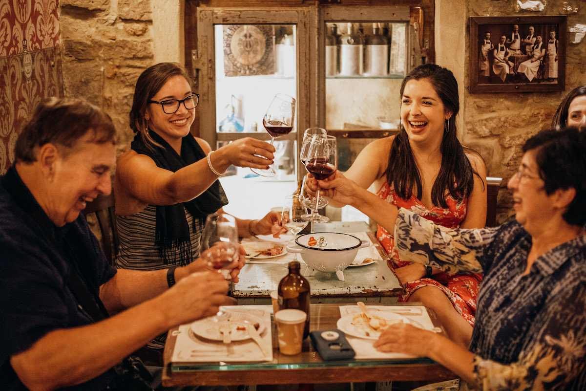 Group of people toasting with red wine around a table